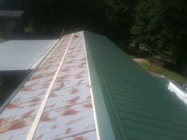 Old rusted panels beside newly installed green metal roofing — Wind Damage Roof Repair by Roofing Brothers in Jamieson