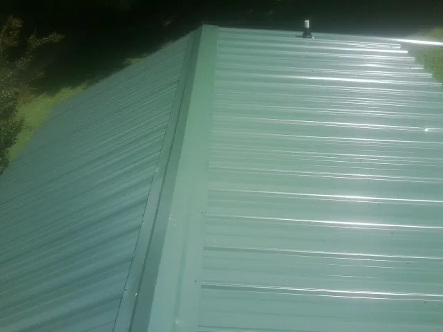 New green metal panels meeting at the ridge of a roof — Flat Roof Repair work by our crew in Jamieson