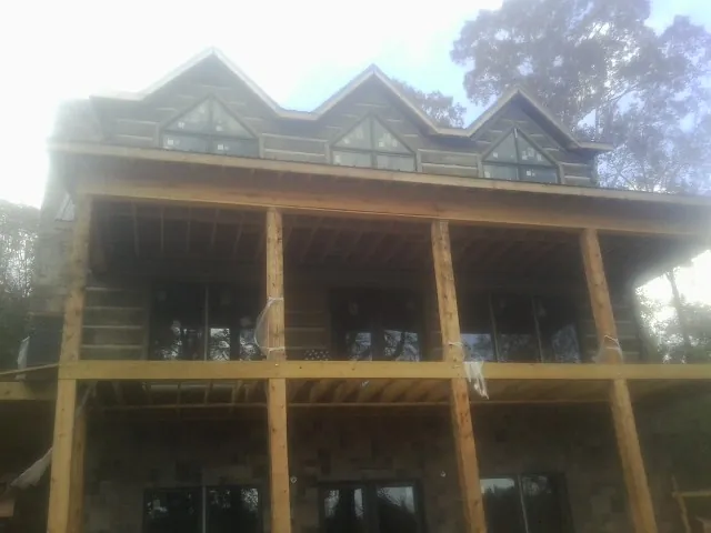 Dormers and porch framing on a large log home under construction — Roof Coating work by our crew in Jamieson