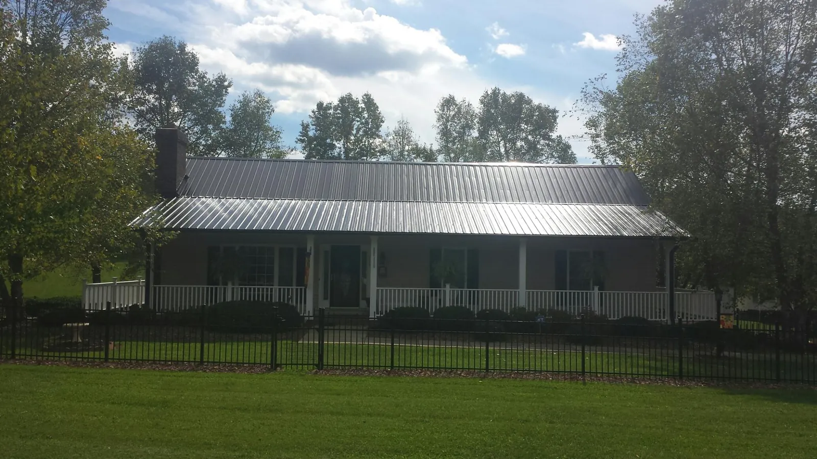 Gray metal roof on a brick ranch with a full width front porch — Gutter Guard Installation work by our crew in Jamieson