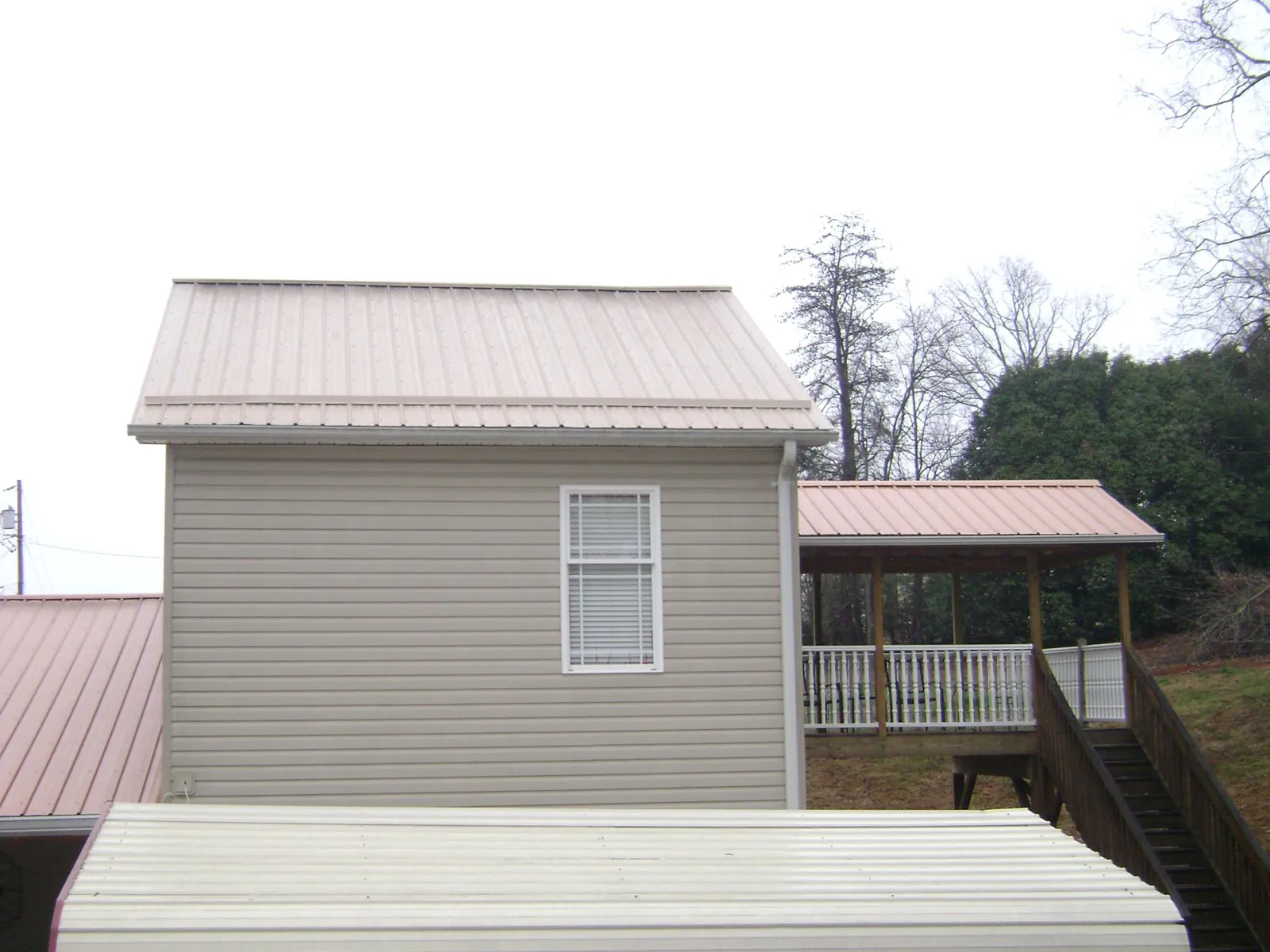 Tan metal roofs on a two story addition and attached porch, from a Roof Replacement job in Jamieson